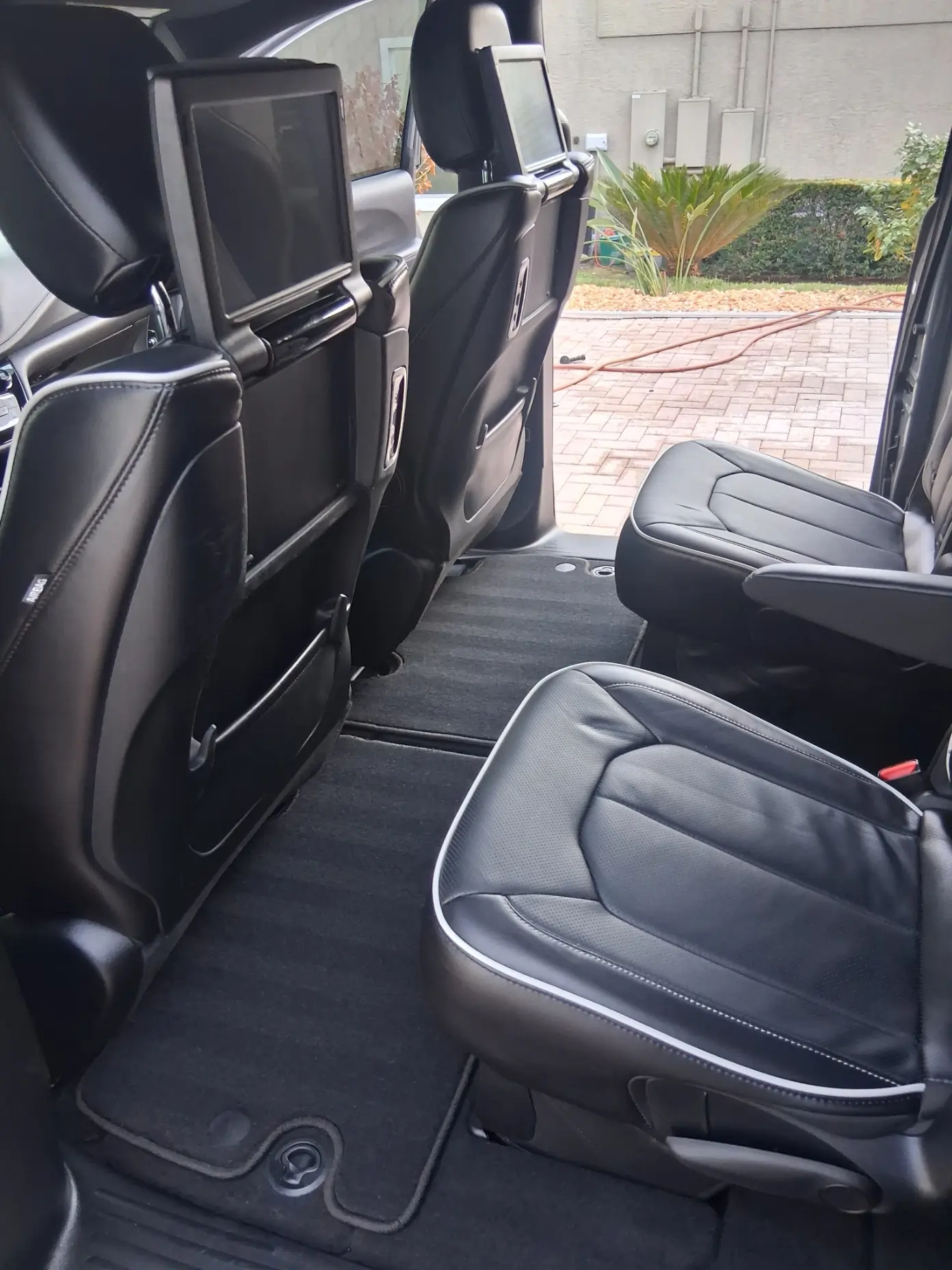 Black leather interior detailing of a luxury SUV featuring rear-seat entertainment screens and vacuumed carpets