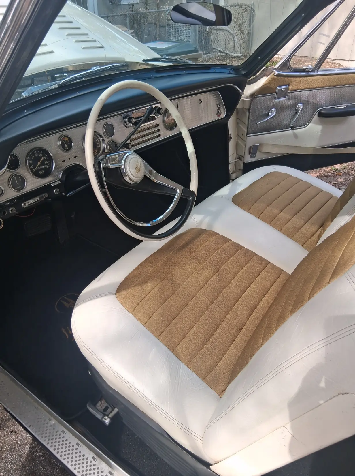 Classic car interior restoration showcasing a vintage dashboard with chrome gauges and white leather bench seating