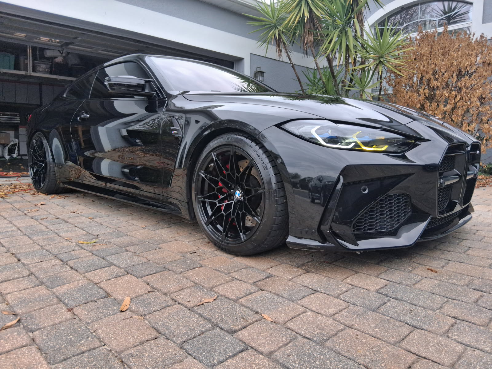 Full detail and paint protection on a gloss black BMW M4 coupe with black multi-spoke wheels and red brake calipers